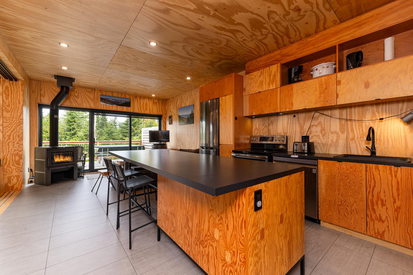 Cuisine moderne en bois avec îlot central et vue sur l'extérieur verdoyant.