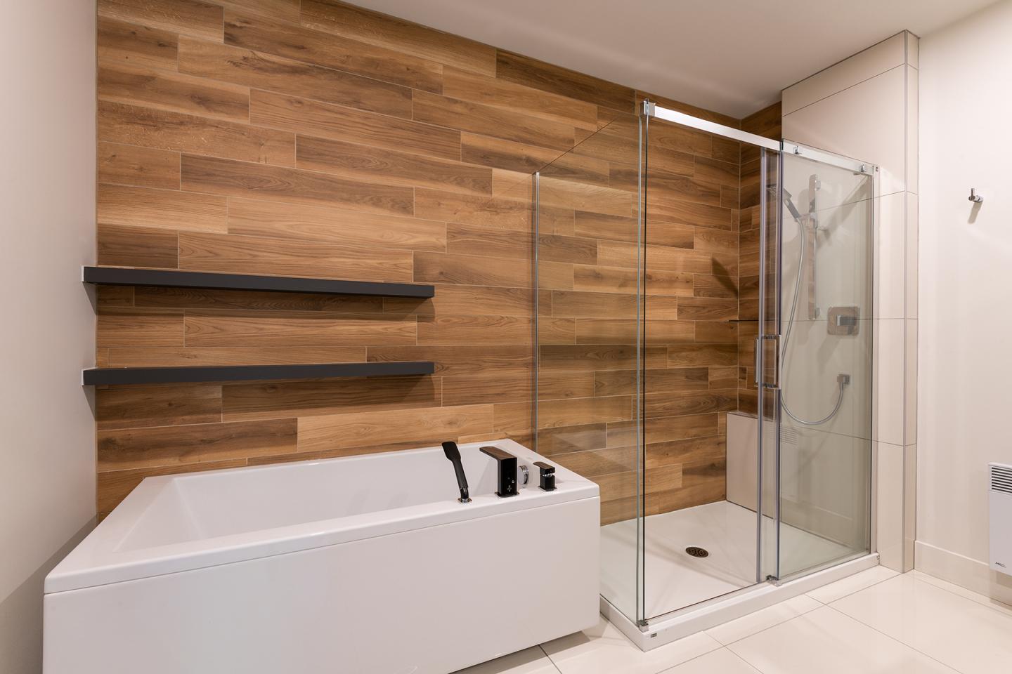 Salle de bain moderne avec baignoire et douche, mur en bois.