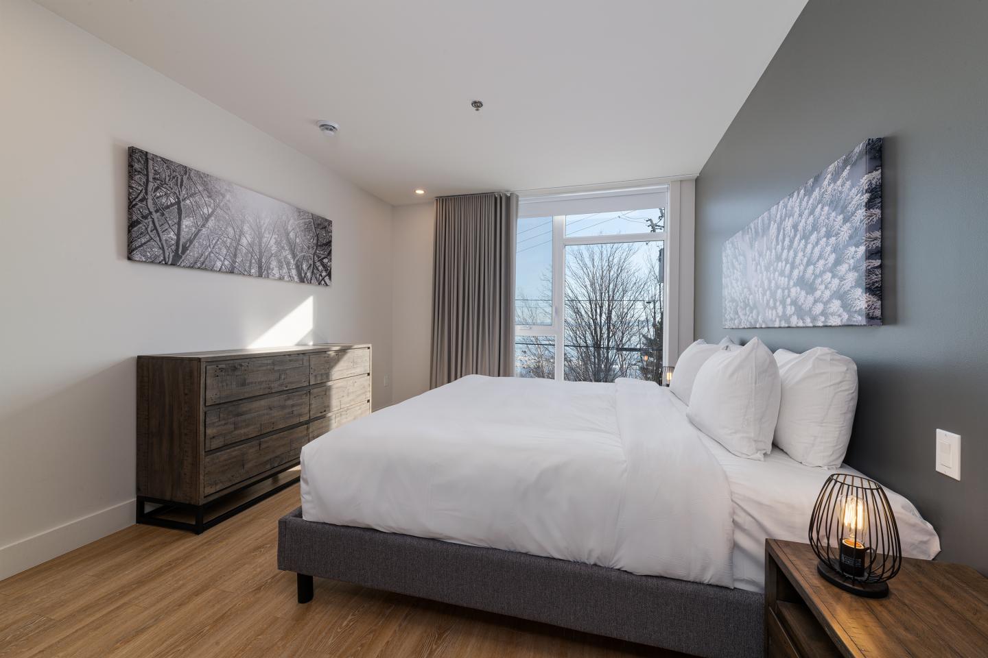 Chambre moderne avec lit double et œuvres d'art, éclairée par une fenêtre.