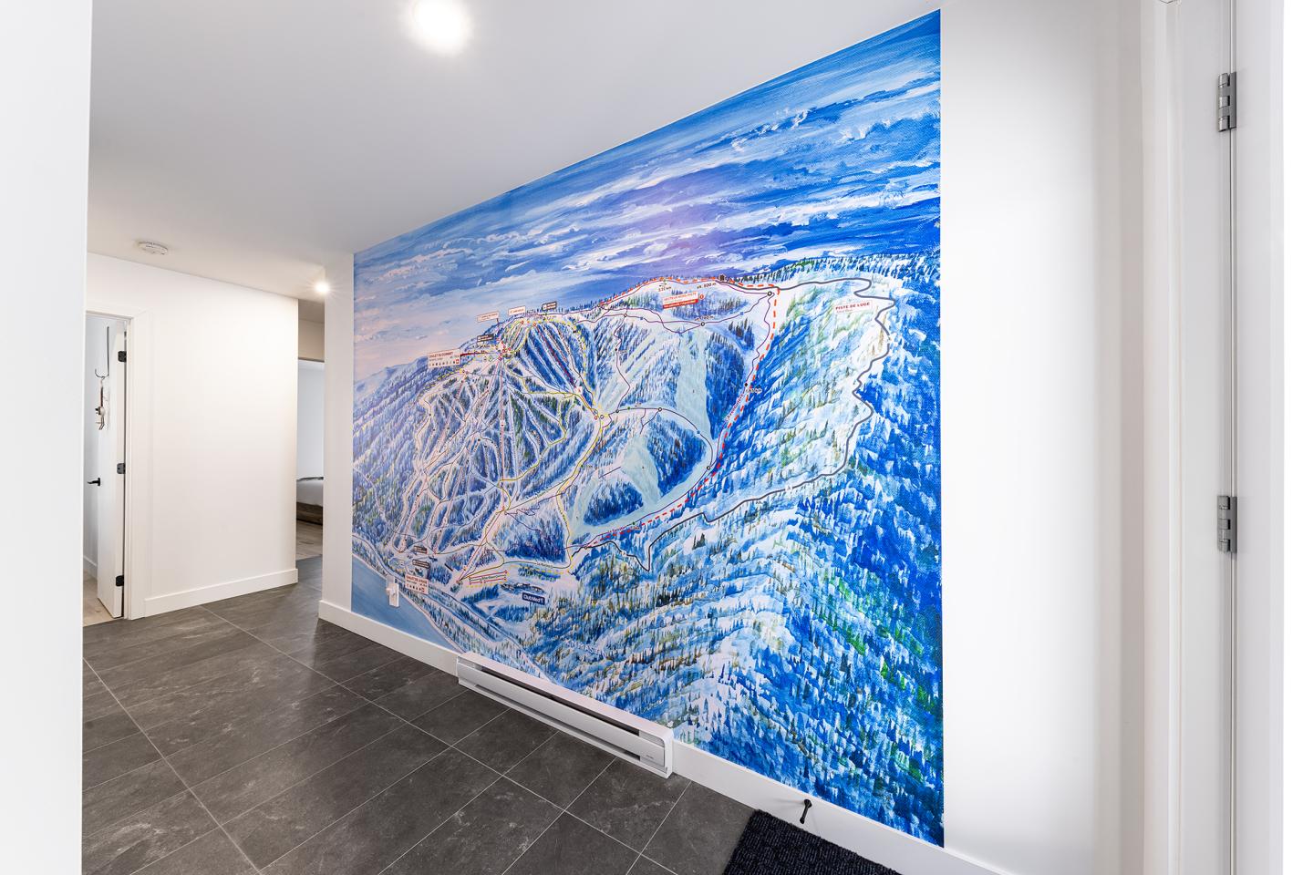 Mur peint d'un paysage montagneux bleu et blanc dans un couloir moderne.