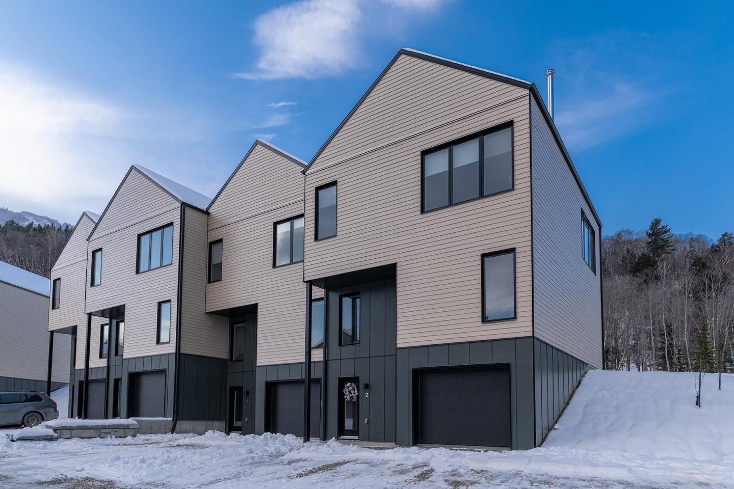 Maisons modernes en rangée sous un ciel bleu, paysage enneigé.