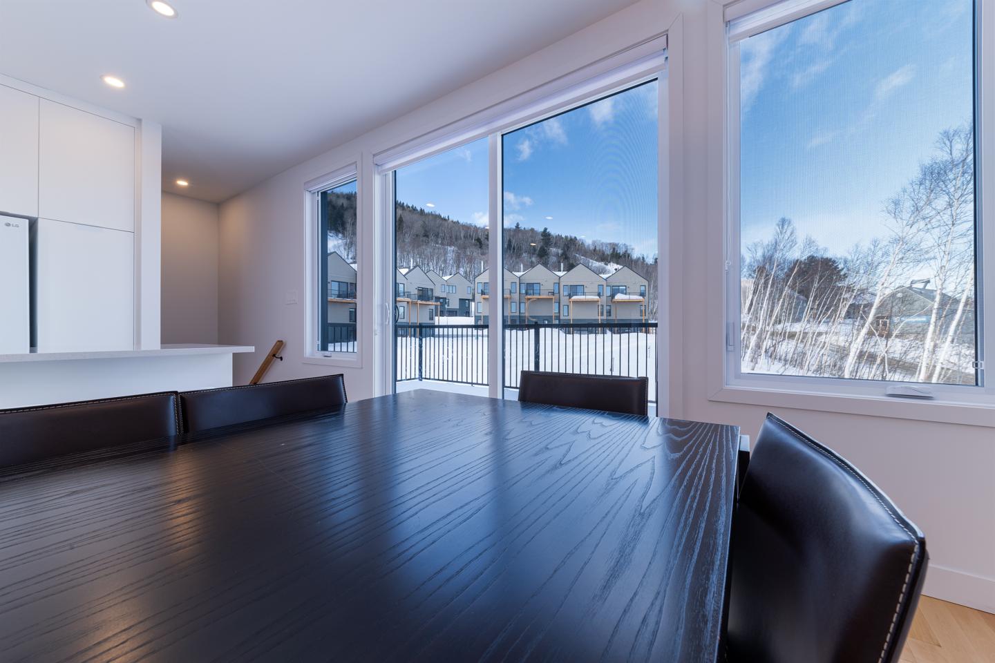 Salle à manger moderne avec vue sur la montagne enneigée par une large baie vitrée.