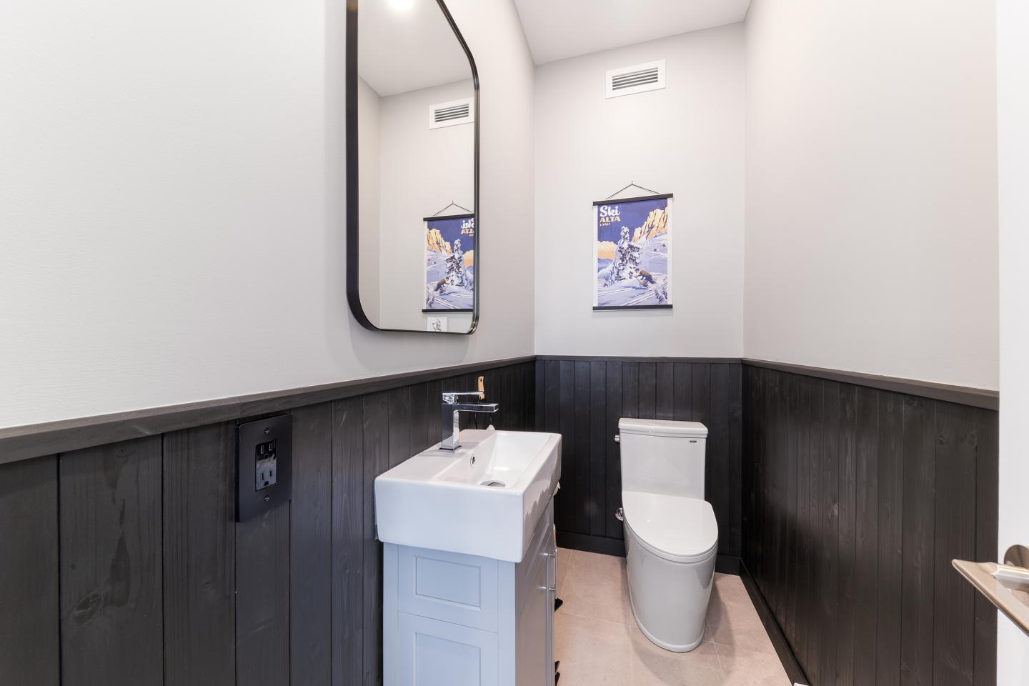 Petite salle de bain moderne avec lavabo, miroir et toilettes.