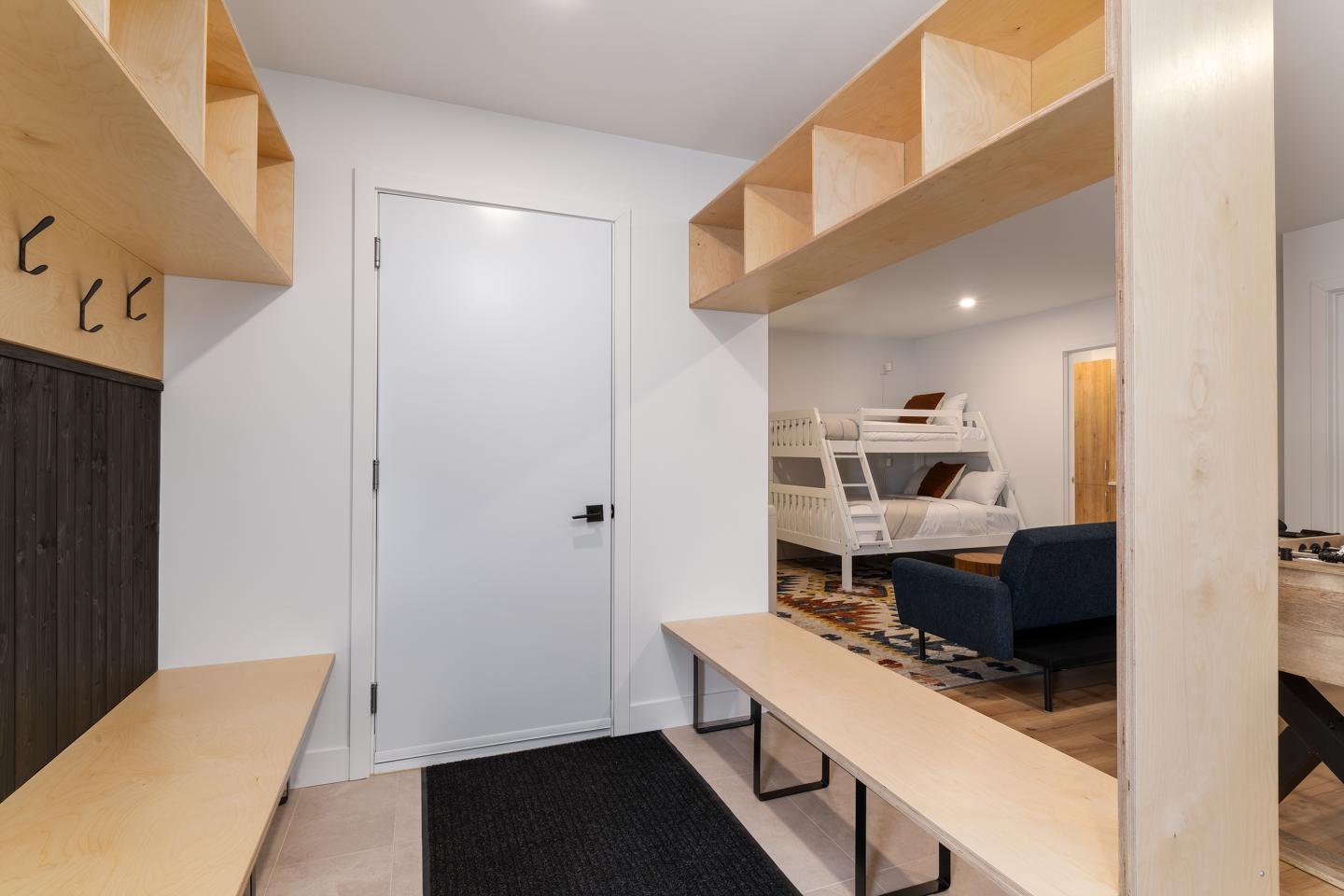 Vestiaire moderne avec bancs en bois, étagères ouvertes et portes blanches.