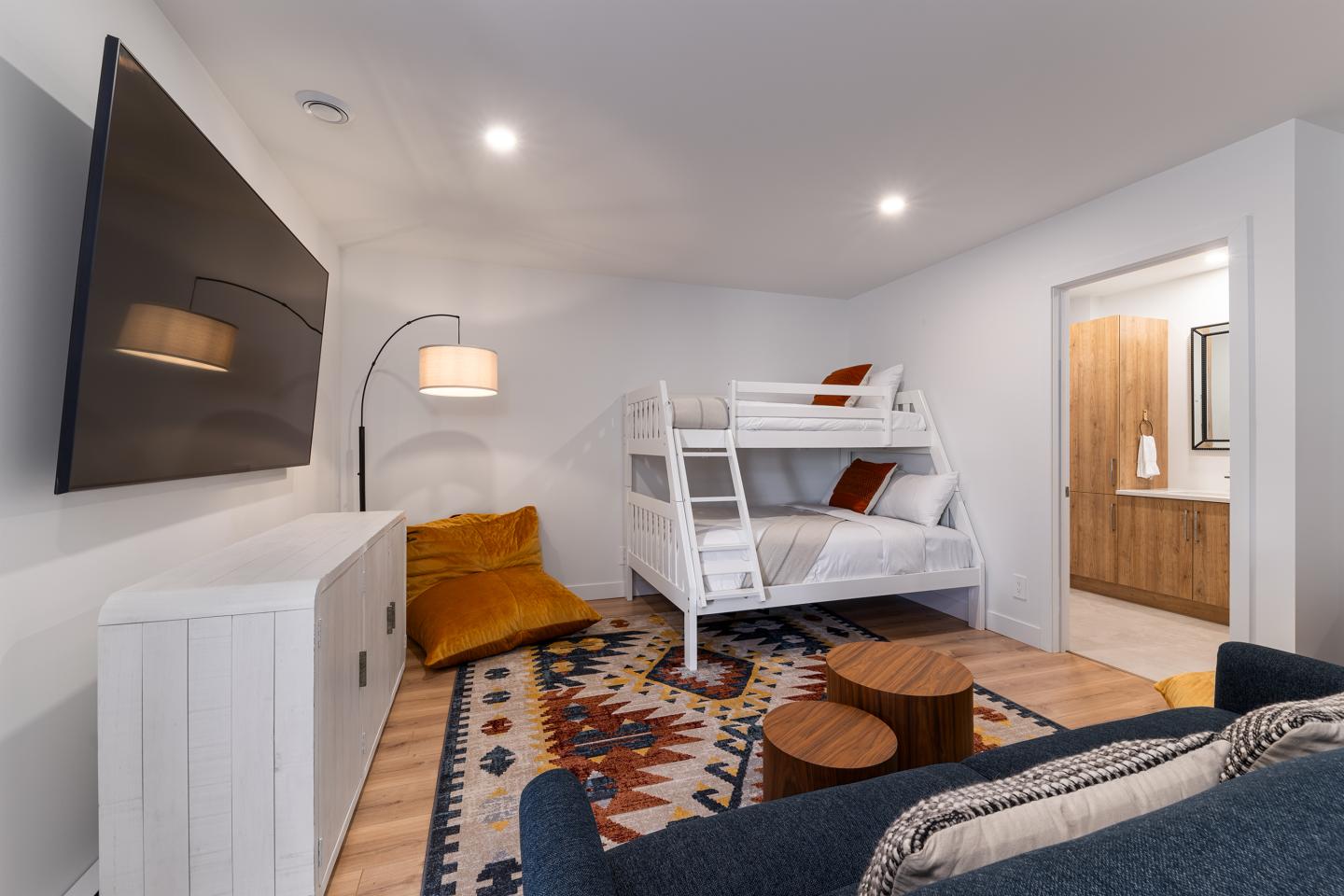 Chambre moderne avec lit superposé, tapis coloré et lampe.