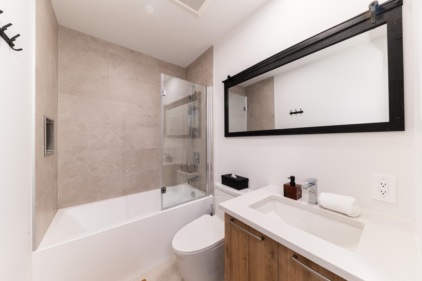 Salle de bain moderne avec baignoire, vasque et grand miroir rectangulaire.
