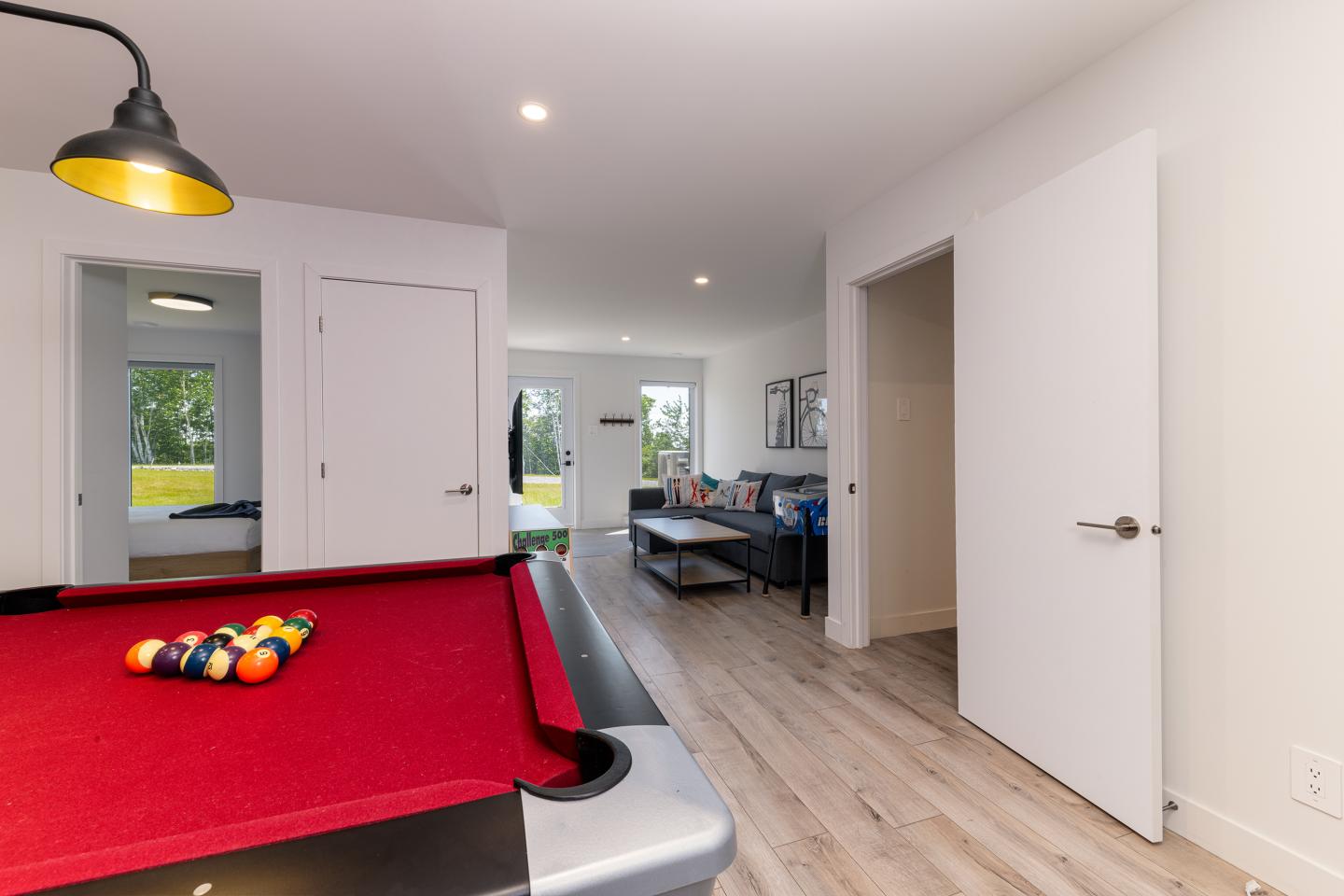 Salle de jeux moderne avec table de billard rouge et lumière suspendue.