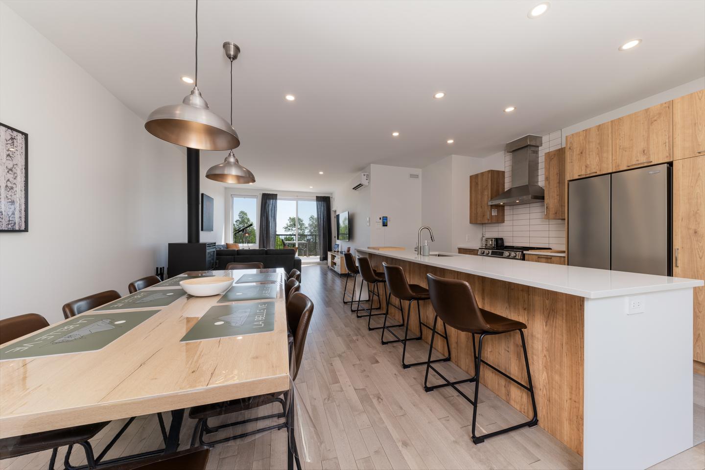 Cuisine moderne avec grande table, îlot central et chaises en bois.