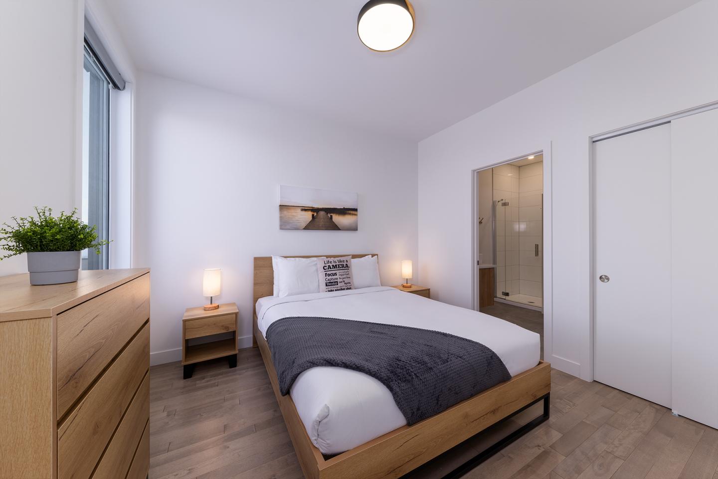 Chambre moderne avec lit double, bois clair, et éclairage doux.