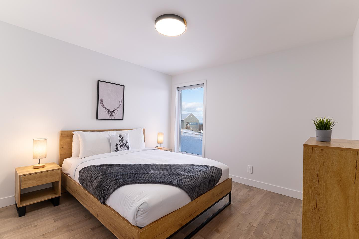 Chambre moderne, lit double, lumière douce, mur blanc, fenêtre avec vue.