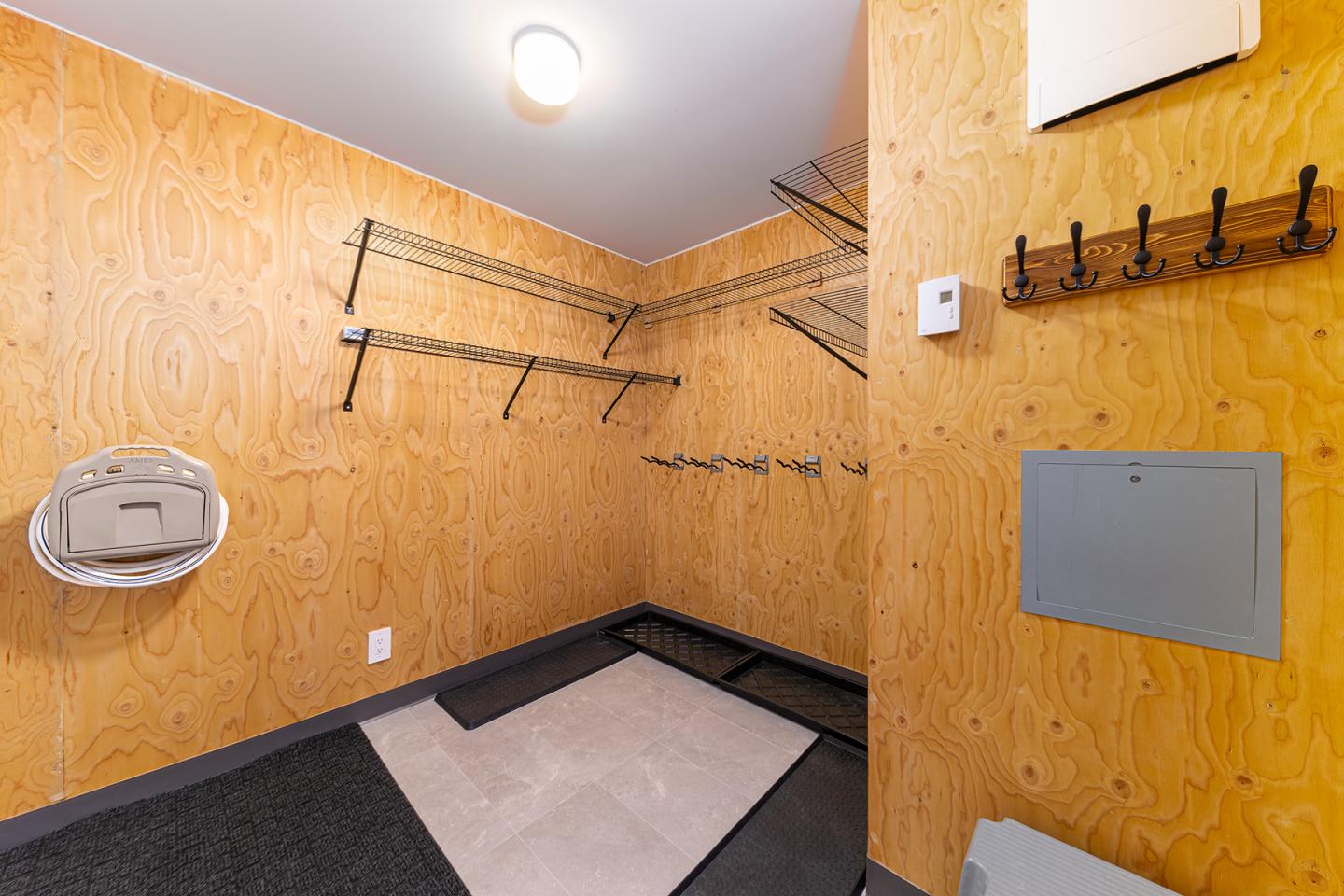 Salle en bois avec étagères et crochets aux murs. Éclairage lumineux.