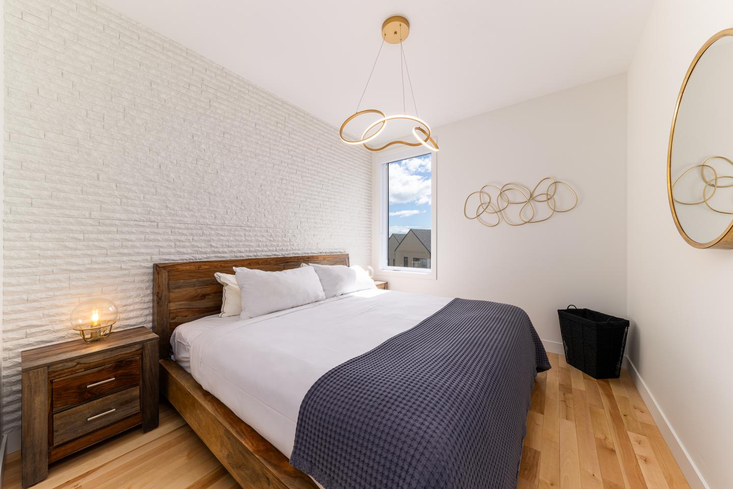 Chambre moderne, lit double en bois, mur blanc, fenêtre avec vue.