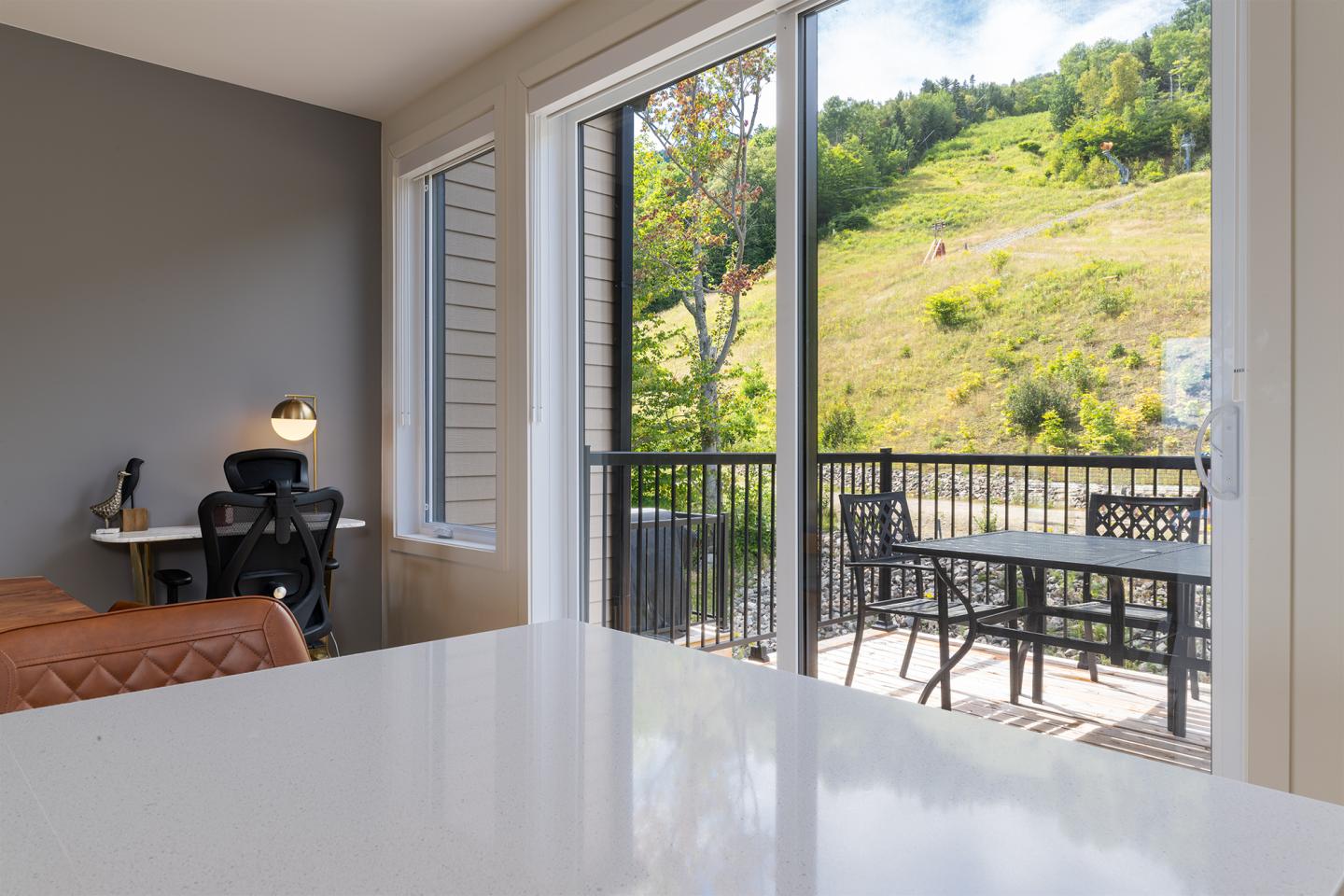 Intérieur moderne avec vue sur terrasse et colline ensoleillée.