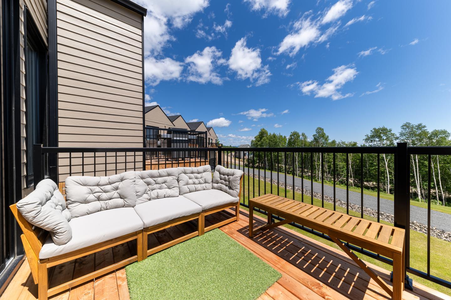 Terrasse ensoleillée avec canapé blanc et banc en bois, ciel bleu.