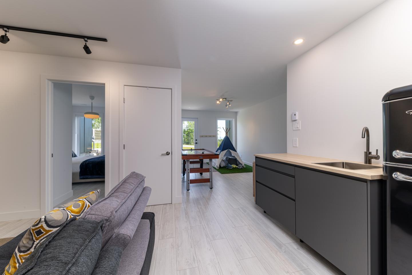 Appartement moderne, salon et cuisine ouverts, décor minimaliste et lumineux.