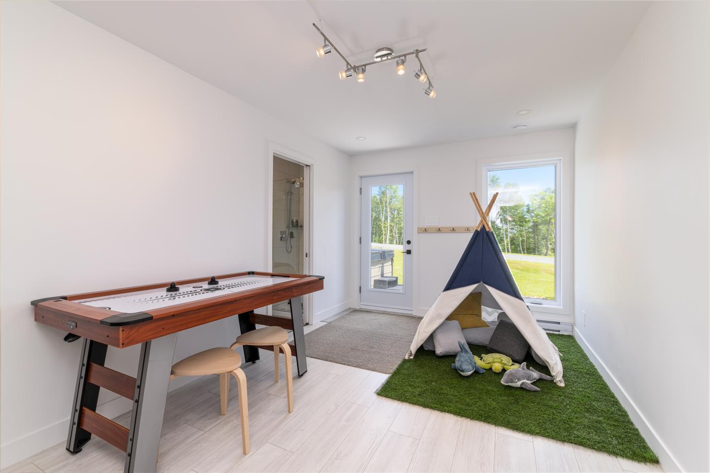 Salle de jeux lumineuse avec tipi et table de hockey sur air.