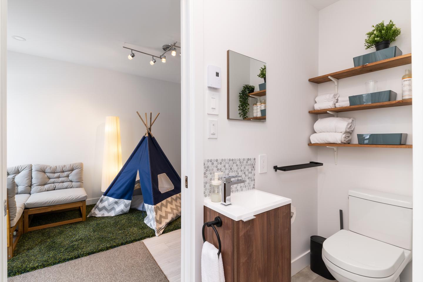 Salle de bain moderne avec étagères et pièce adjacente avec tente bleue.