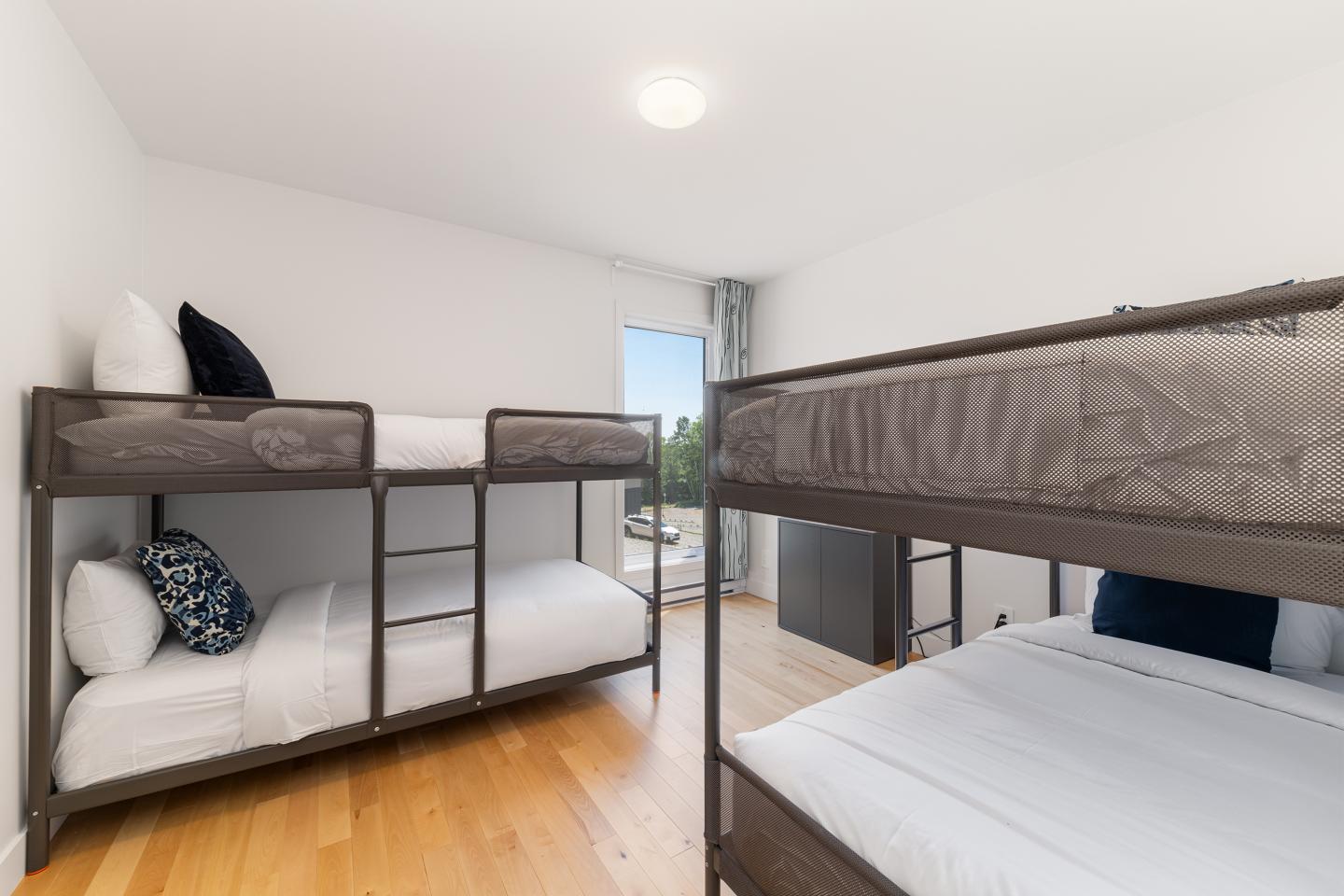 Chambre lumineuse avec lits superposés et parquet clair.