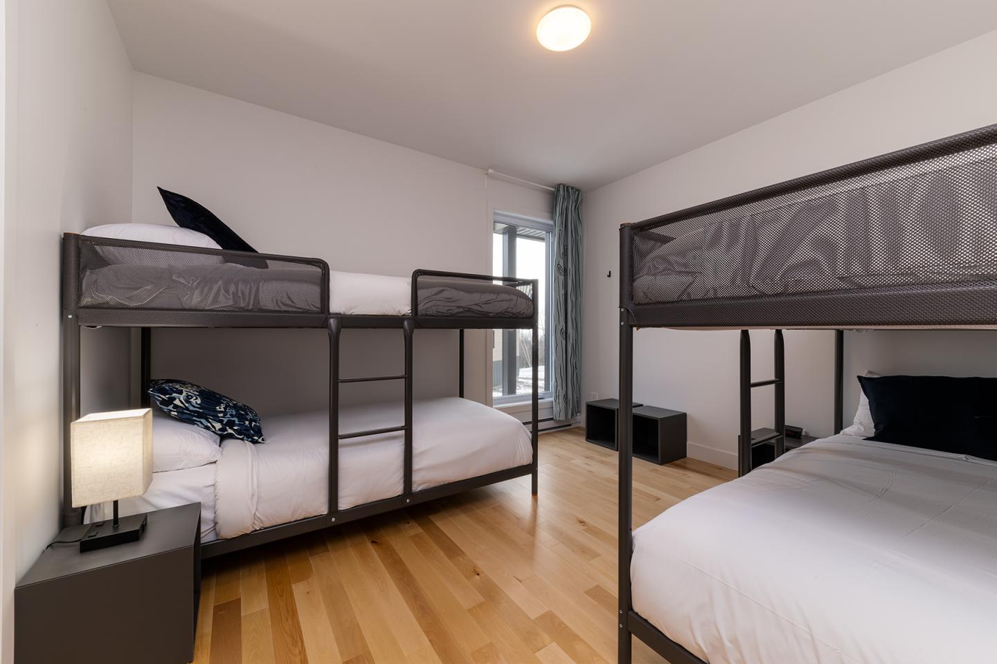Chambre avec trois lits superposés, sol en bois clair.