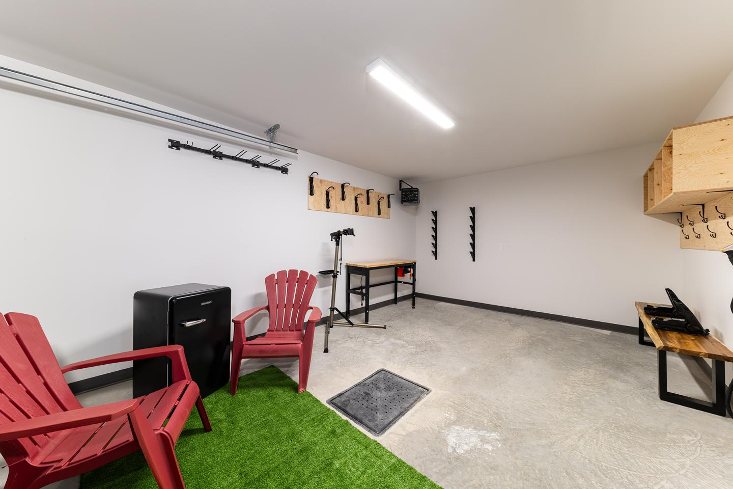 Garage propre avec chaises rouges, étagères, et sol partiellement gazonné.