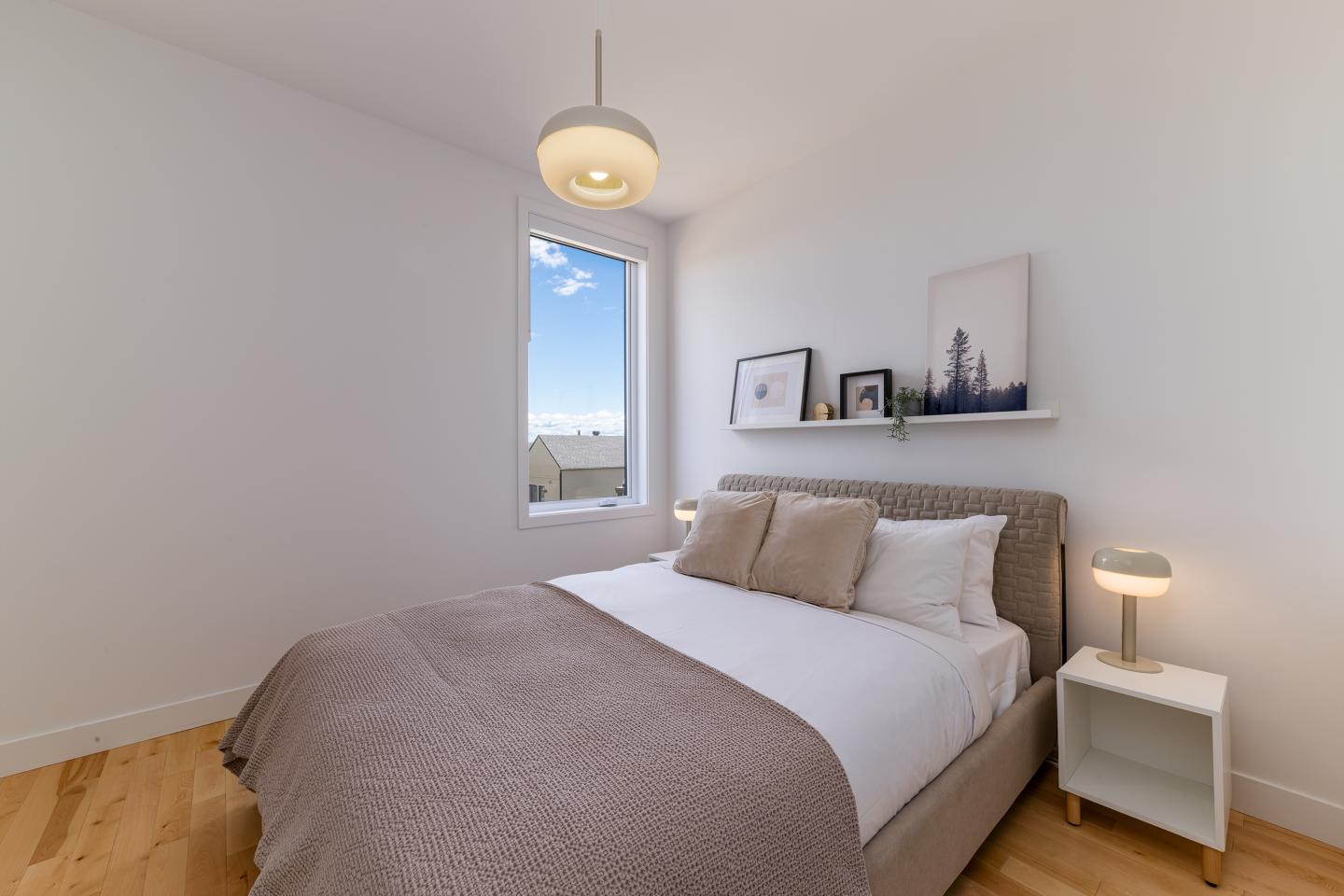 Chambre lumineuse avec un lit double et deux tables de chevet, déco minimaliste.