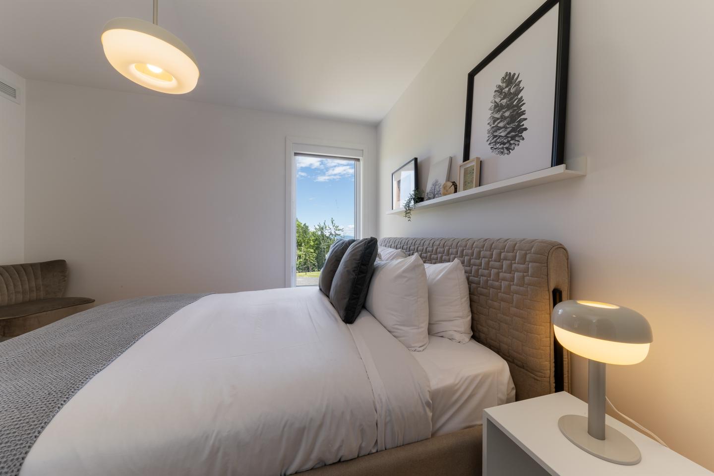 Chambre lumineuse avec lit double, lampe et tableau.