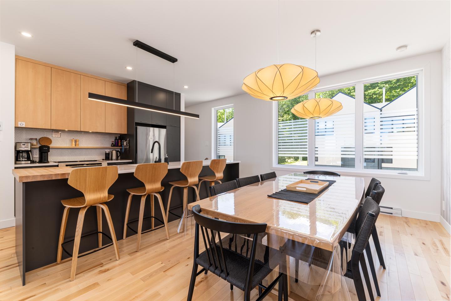 Cuisine moderne avec table à manger en bois, chaises et luminaires design.