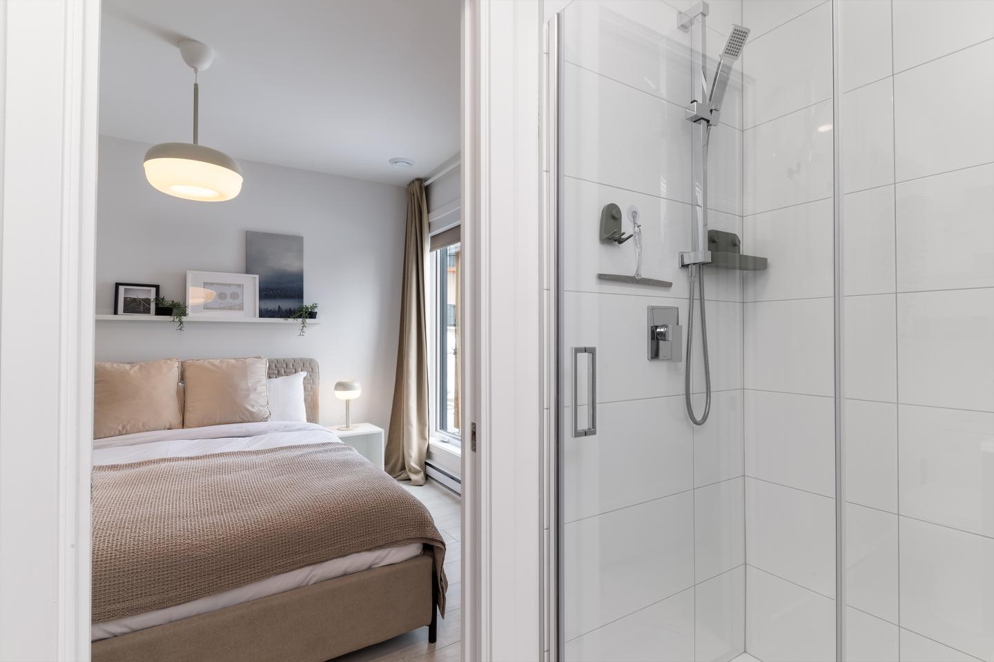 Chambre moderne avec lit double et douche à proximité.
