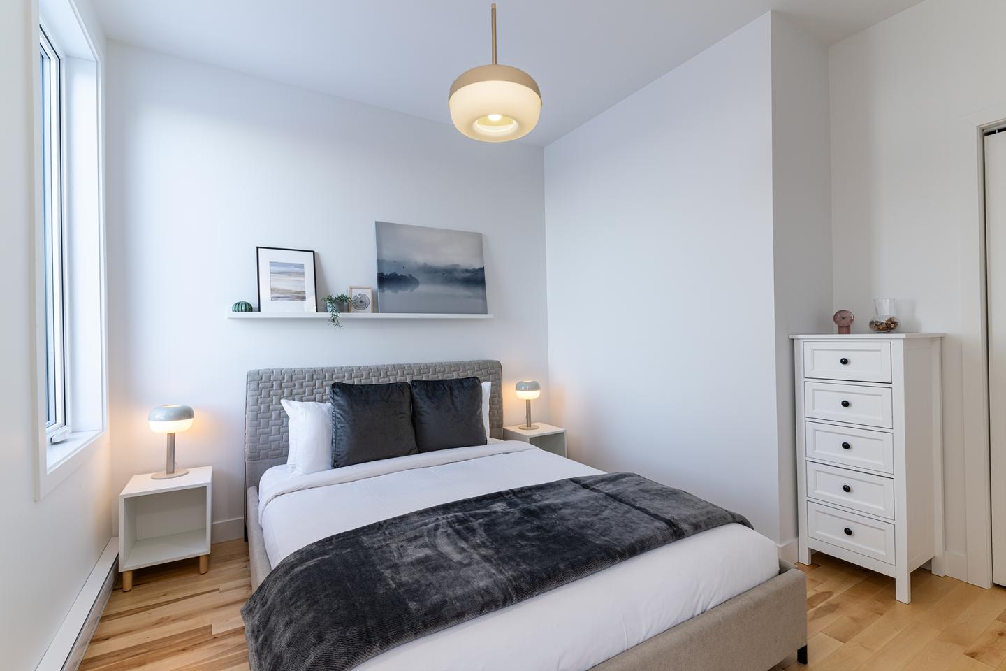Chambre moderne avec lit double et décoration minimaliste, tons neutres.