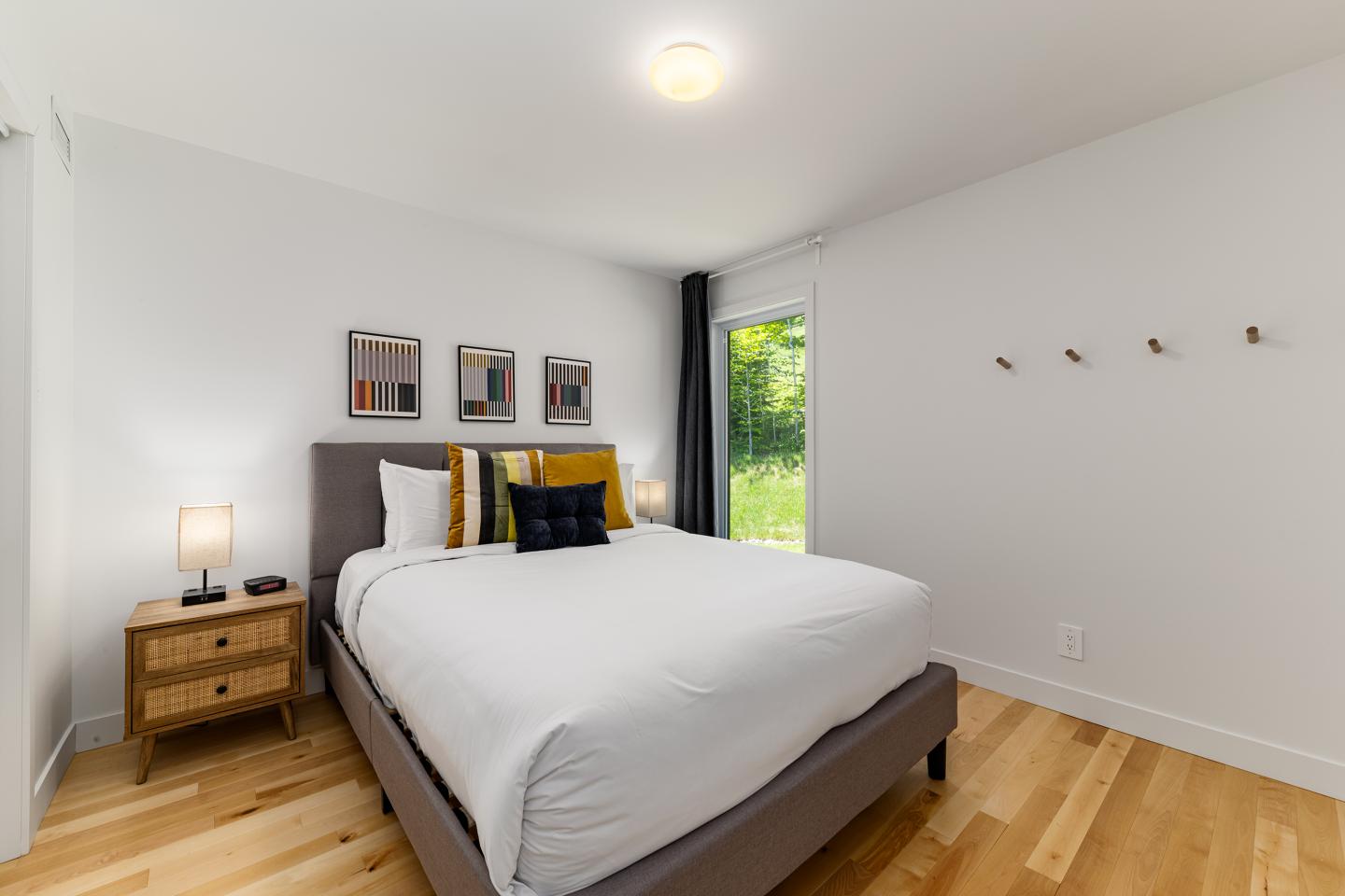 Chambre moderne avec lit double, table de chevet et fenêtre lumineuse.