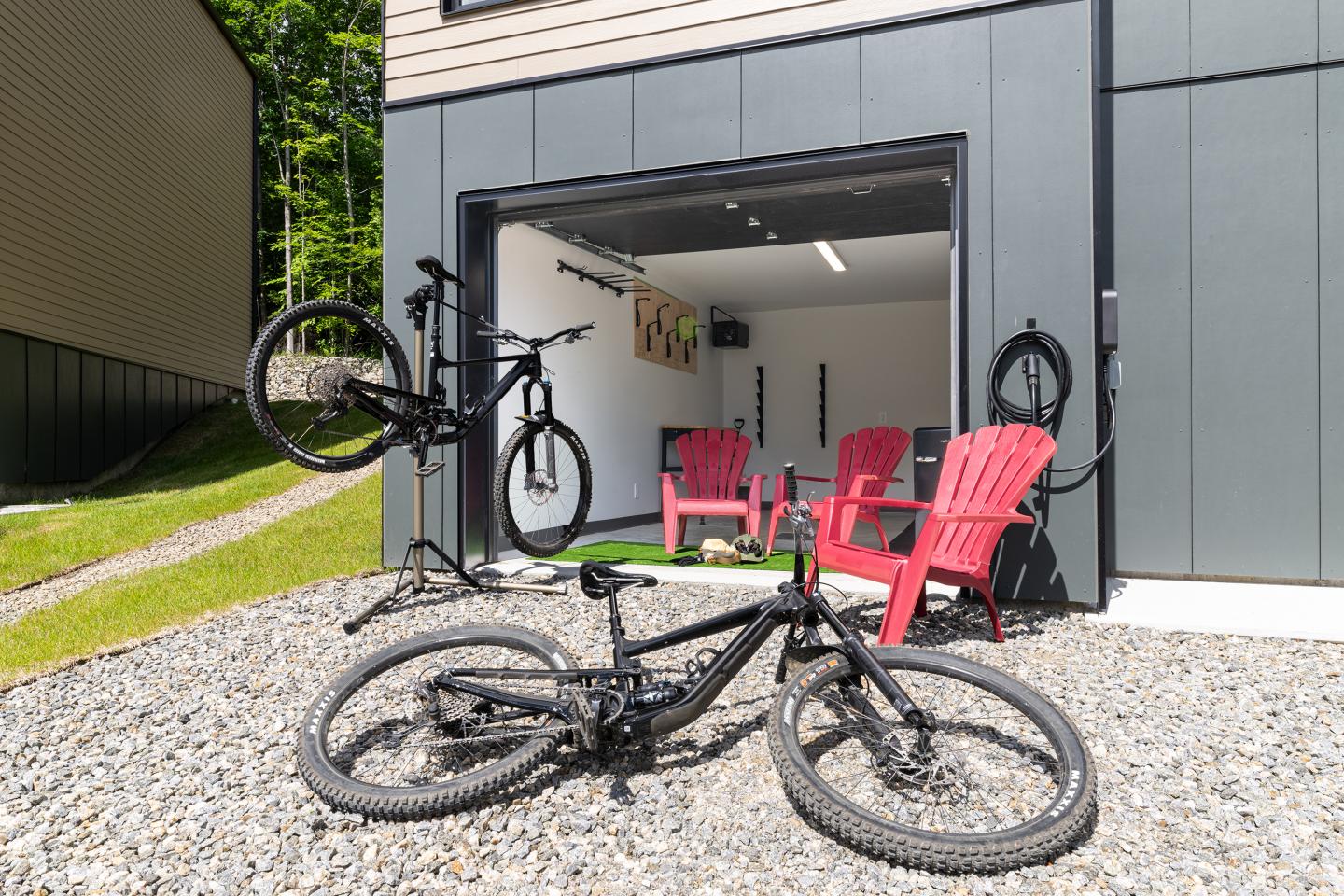 Garage ouvert avec vélos noirs et chaises rouges devant.
