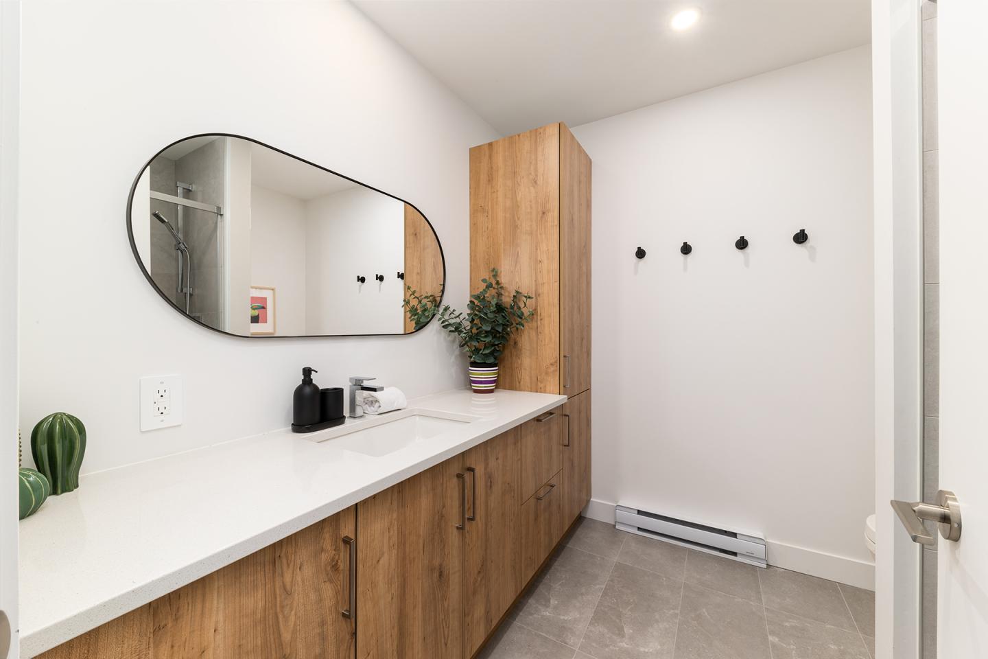 Salle de bain moderne, miroir ovale, plan de travail en bois, plantes.