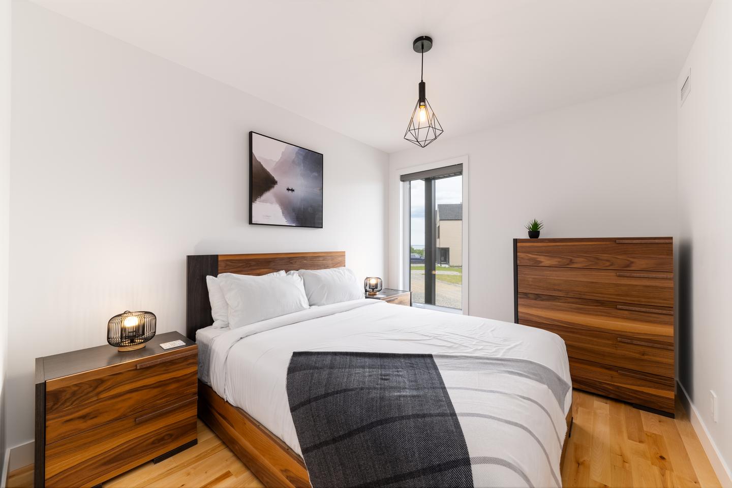 Chambre contemporaine avec lit double, mobilier en bois, et lumière naturelle.