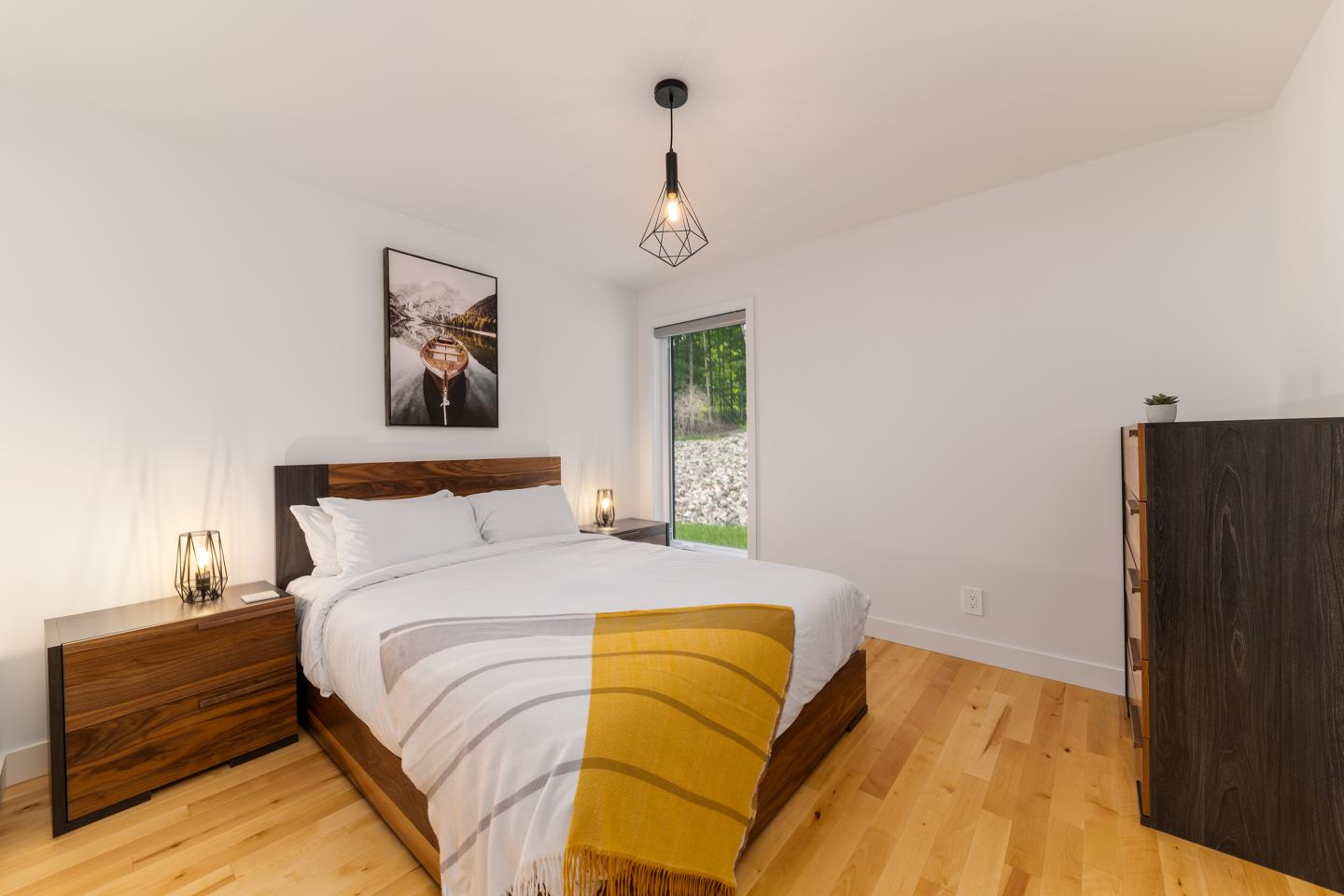 Chambre lumineuse avec lit double, décor minimaliste et parquet clair.