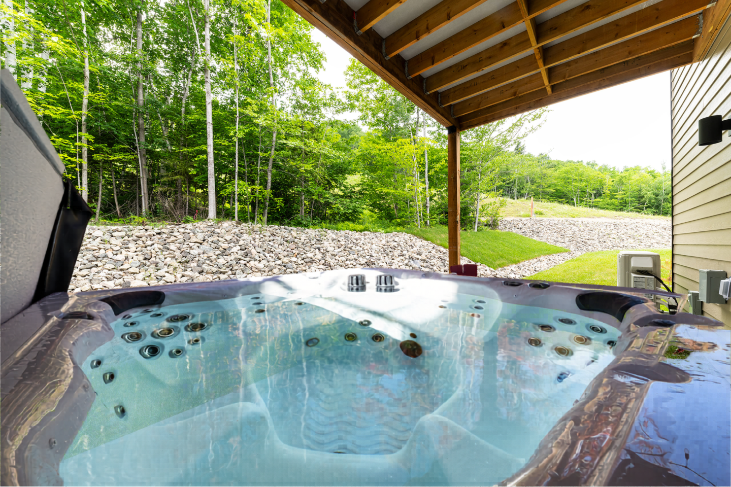 Jacuzzi sous un patio avec vue sur un jardin arboré, ciel dégagé.