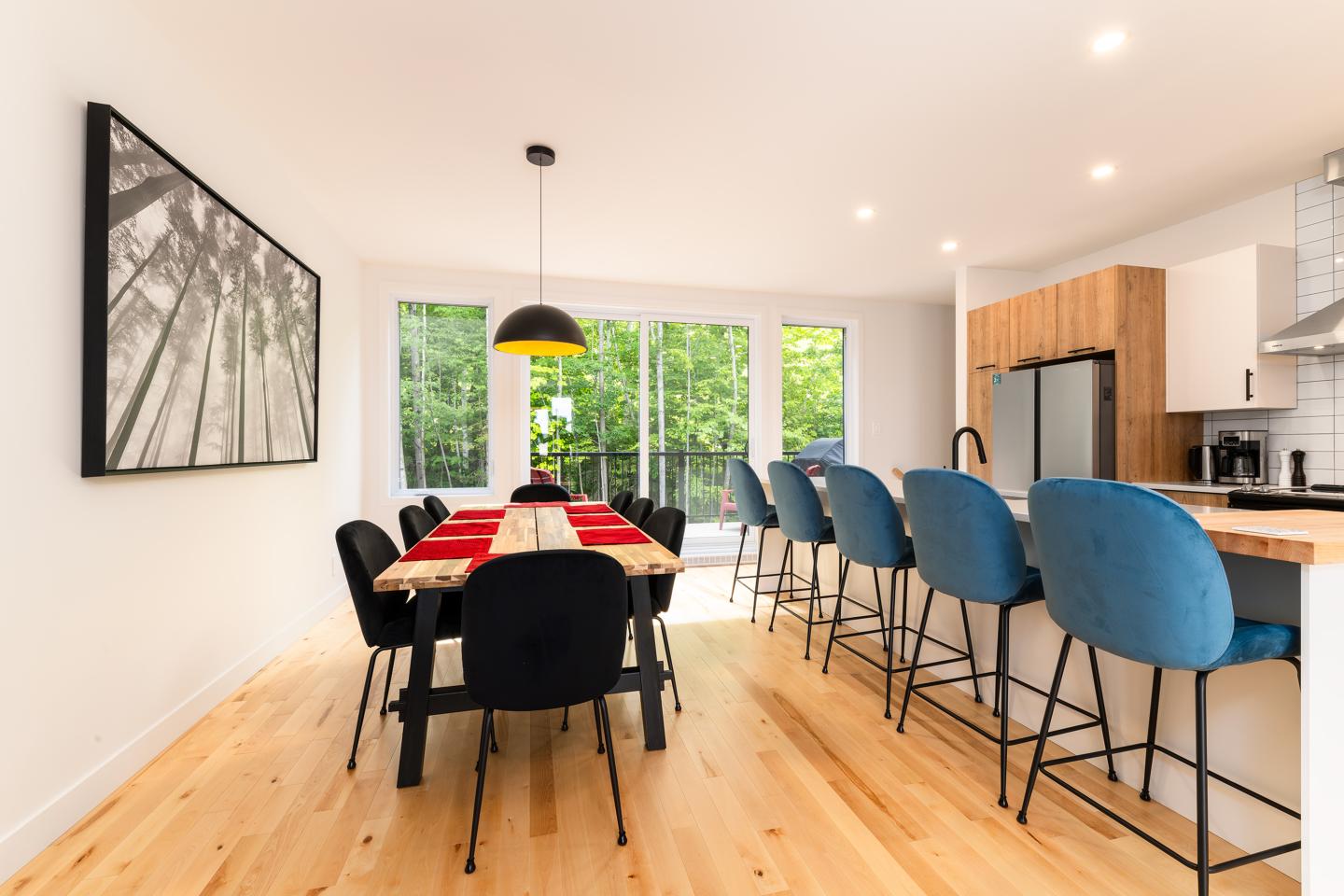 Salle à manger moderne, table bois, chaises noires, fenêtre sur jardin.