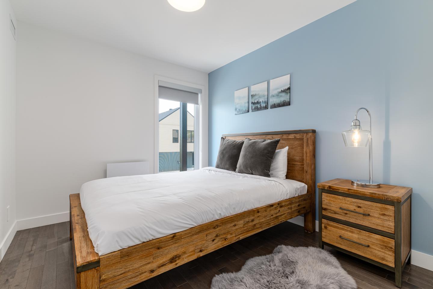 Chambre simple avec lit en bois, murs bleu et blanc, et table de chevet.