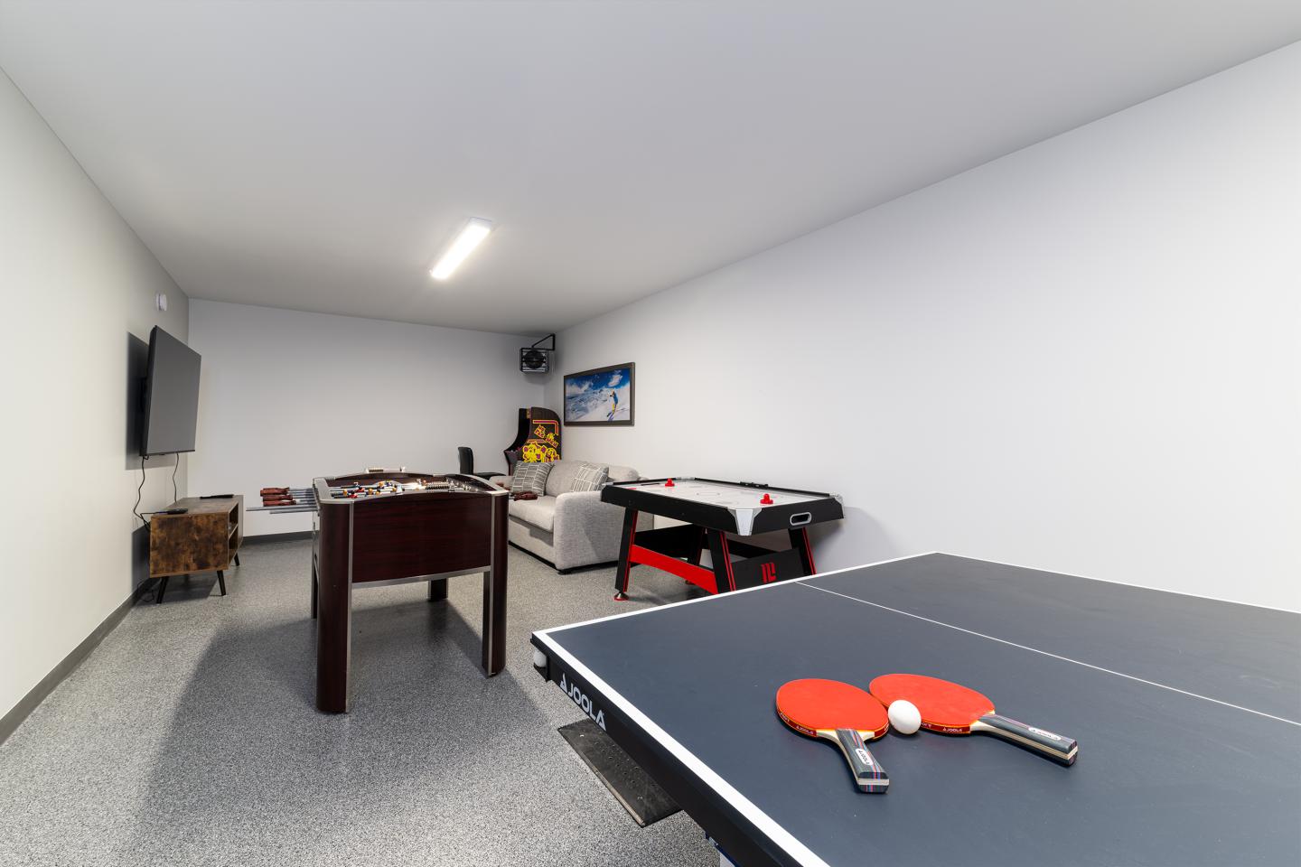 Salle de jeux avec table de ping-pong, baby-foot et air hockey.