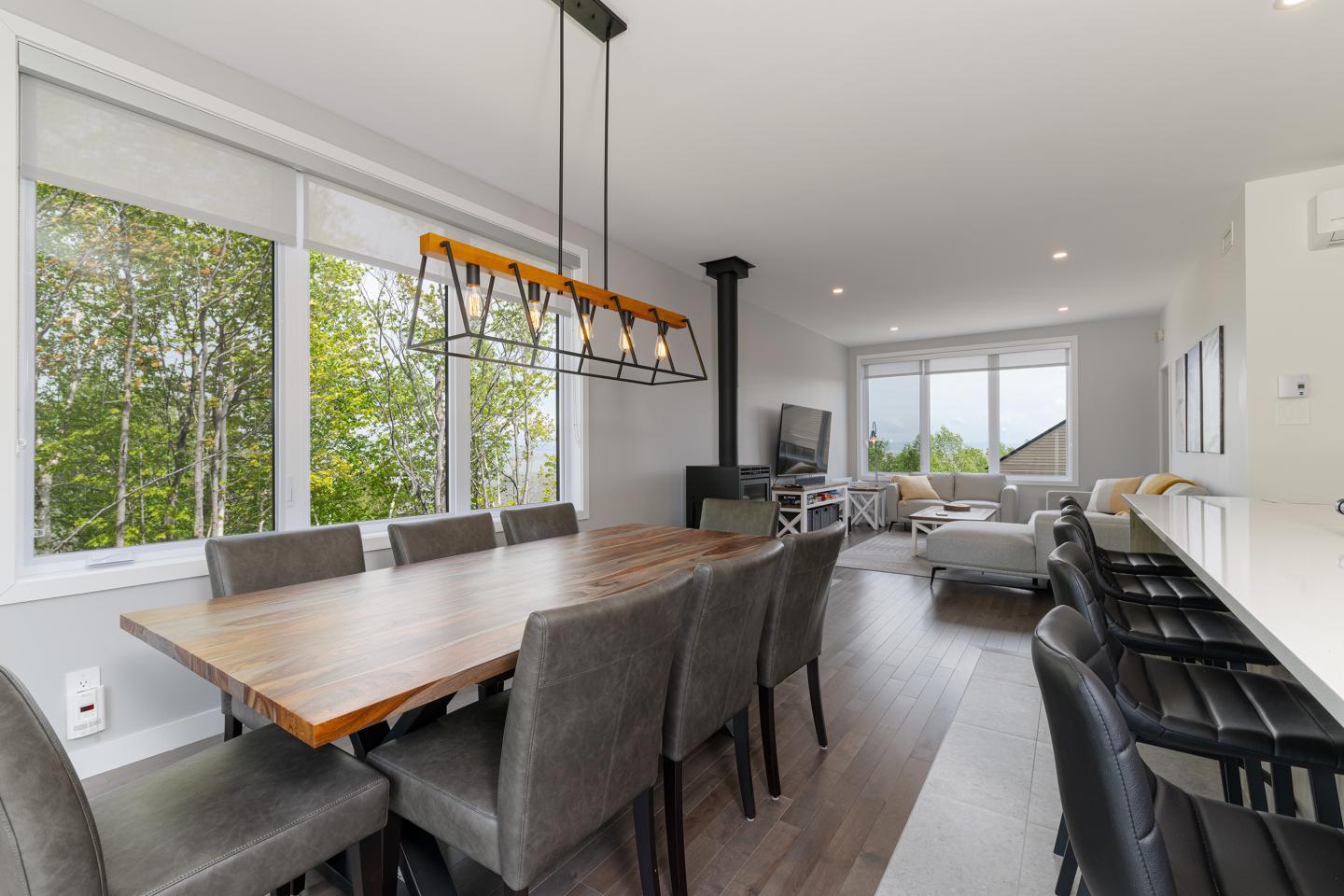 Salle à manger moderne avec table en bois et chaises grises, canapé blanc en arrière-plan.