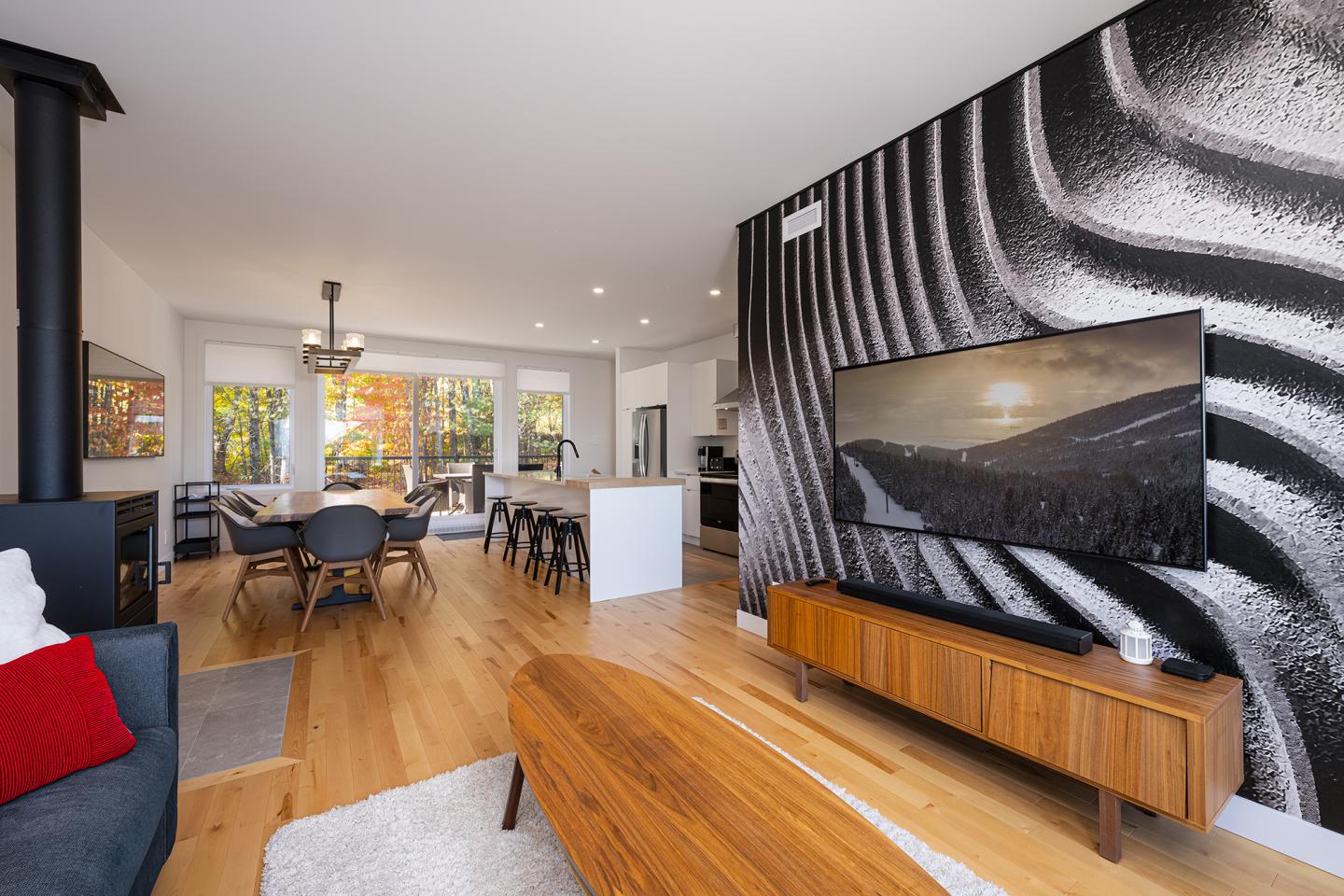 Salon moderne avec TV et mur noir et blanc, sol en bois clair.
