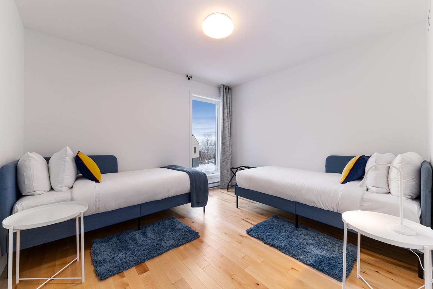 Chambre moderne avec deux lits simples et décoration bleue et blanche.
