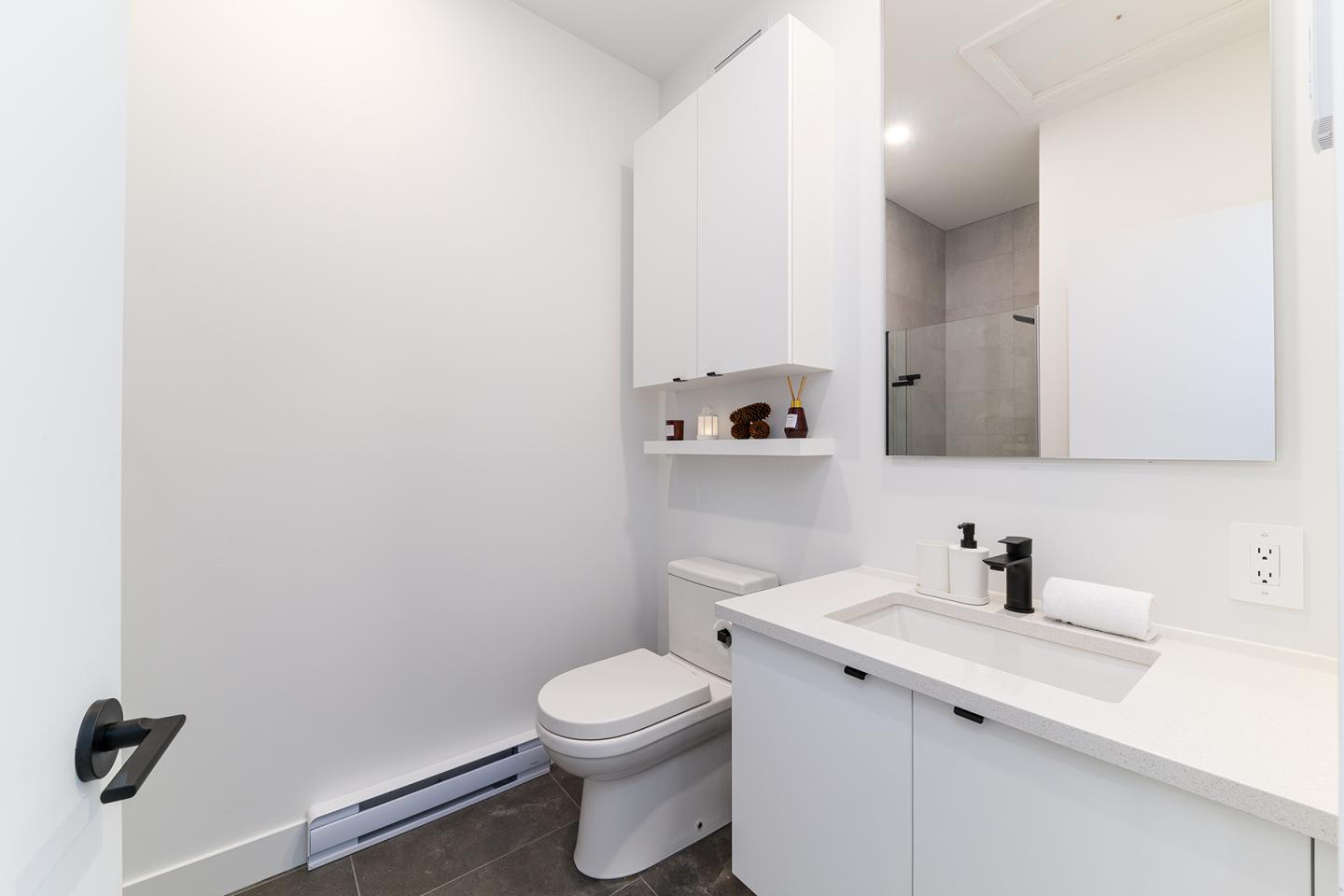 Salle de bain moderne avec lavabo, toilette et armoire blanche.