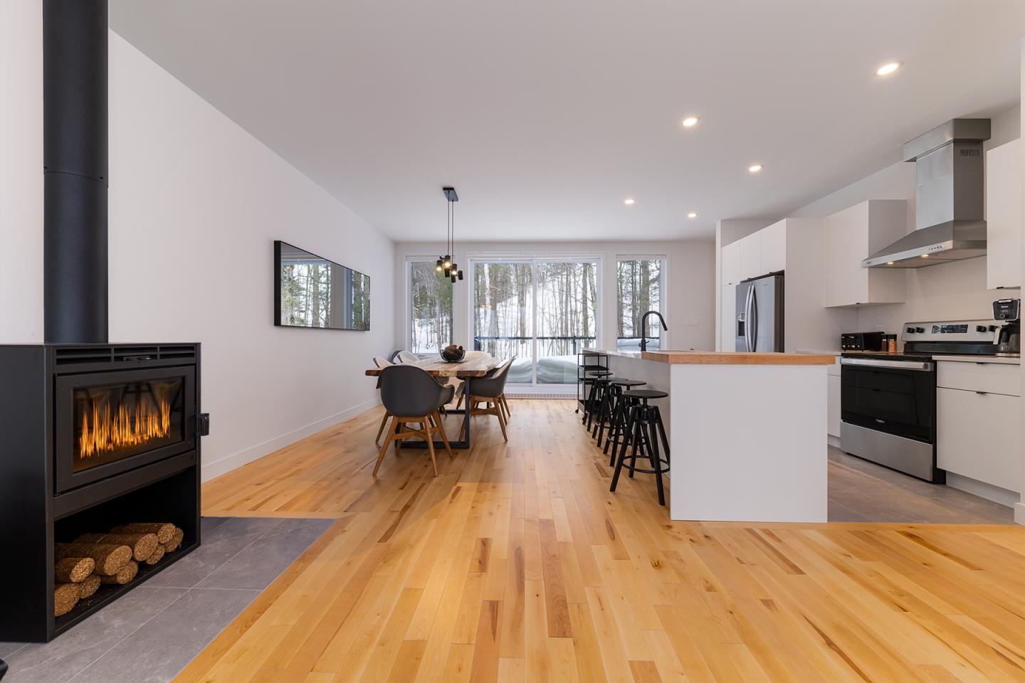 Cuisine moderne avec sol en bois, cheminée et grande table à manger.