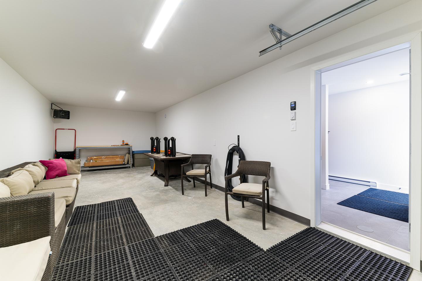 Salle blanche avec canapé, fauteuils et table. Luminaire au plafond.