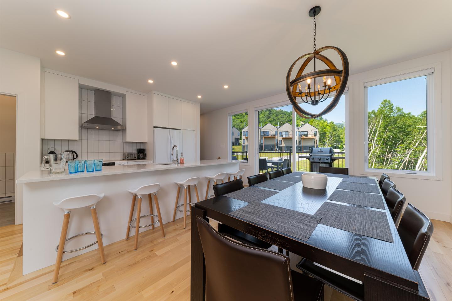 Cuisine moderne avec îlot central et table à manger, vue sur le jardin.