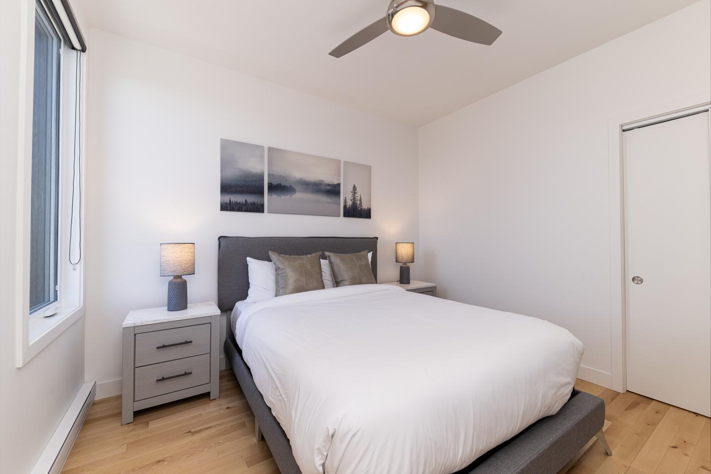 Chambre lumineuse avec lit double, lampes de chevet et tableau mural.