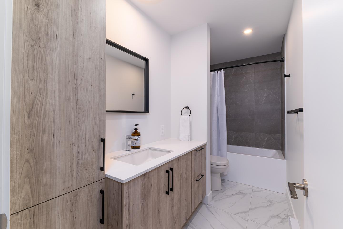 Salle de bain moderne avec lavabo, baignoire et sol en marbre.