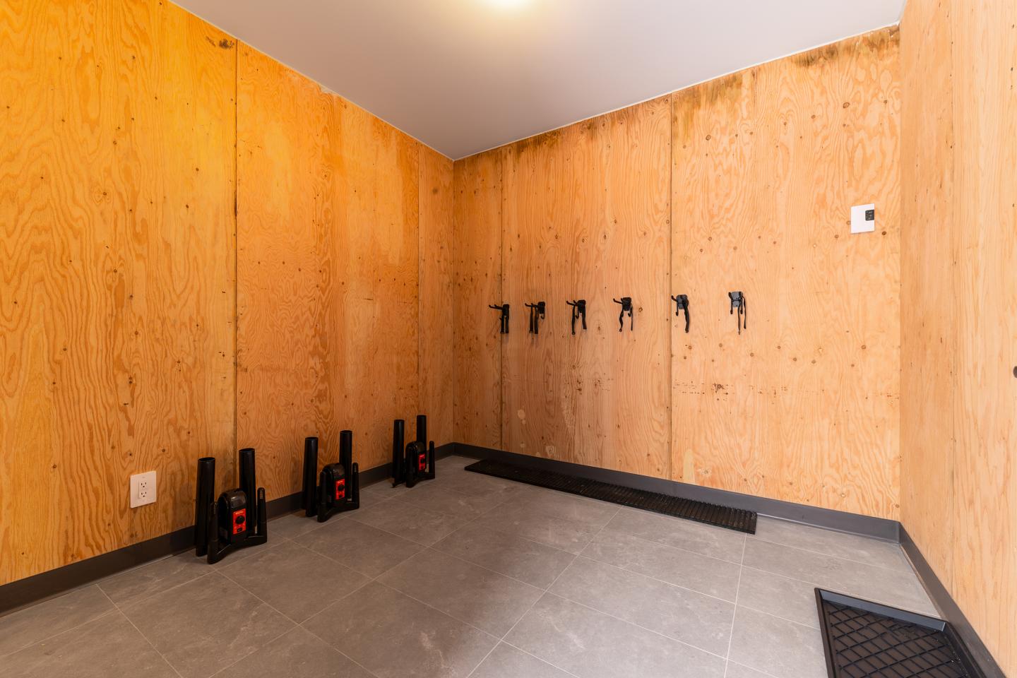 Salle en bois clair avec crochets muraux et équipements au sol.
