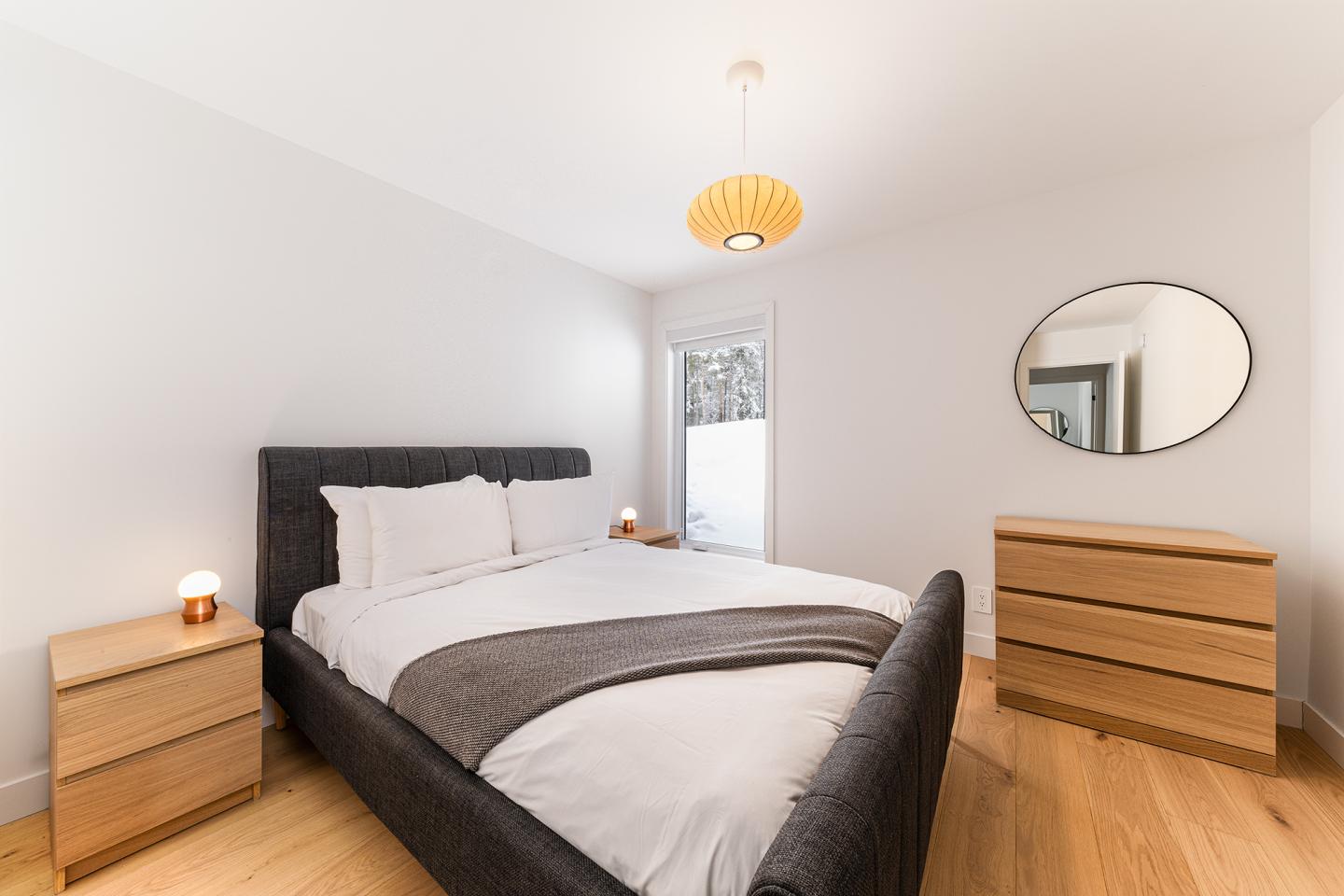 Chambre moderne avec lit double, commodes et miroir ovale.