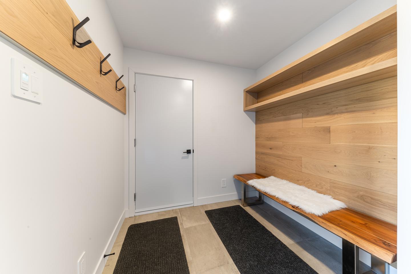 Vestiaire moderne avec banc en bois et patères murales.